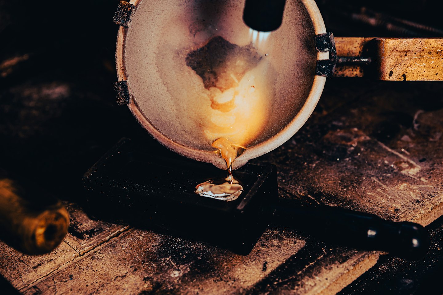 Molten metal poured into a mold on a wooden workbench.