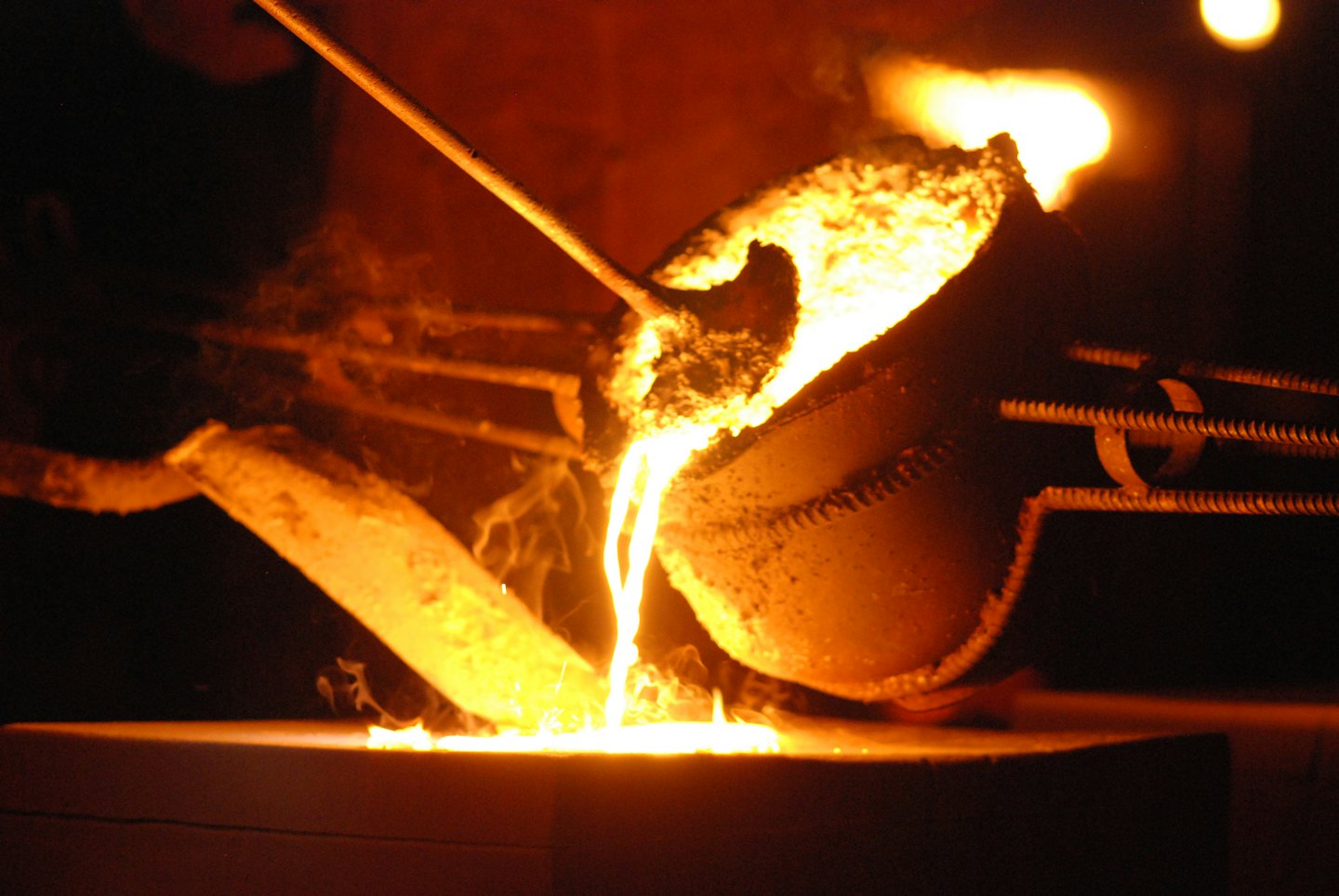 Molten metal flows from a ladle into a mold.