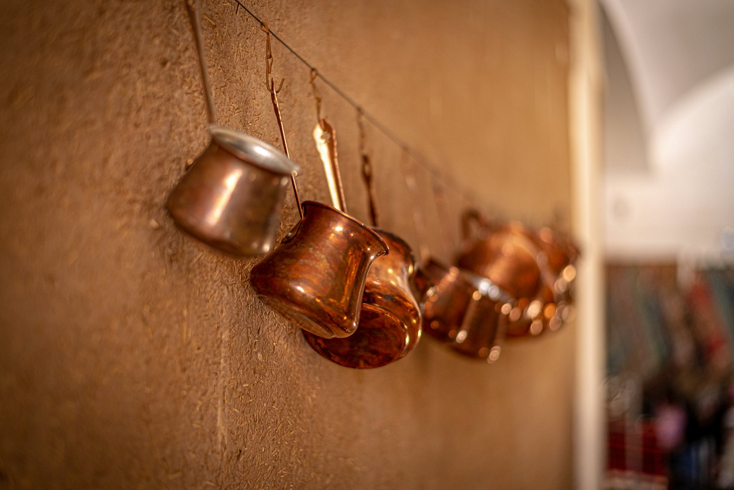 Polished copper pots and pitchers hanging on a wall.